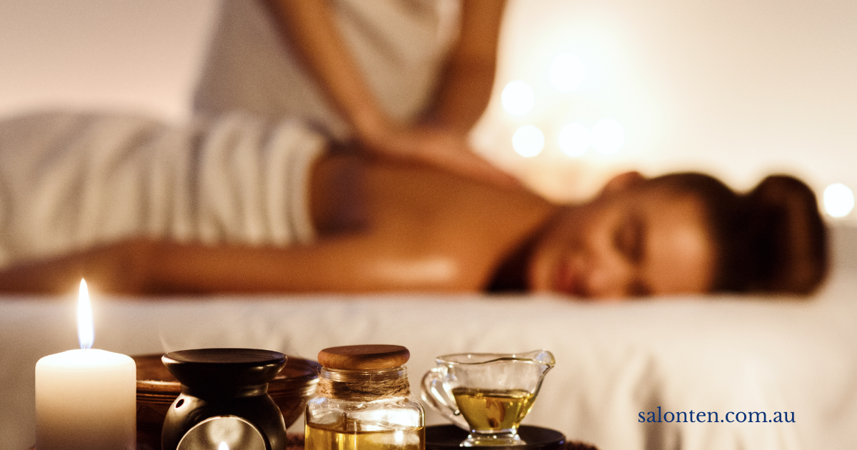 Warm oil back massage by candlelight, with massage oils and a candle in the foreground