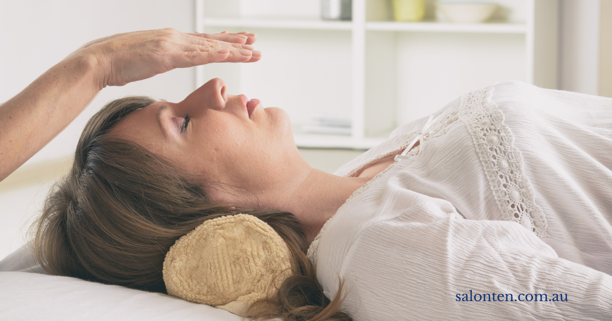 Reiki treatment in progress, hands held above a resting client&rsquo;s head